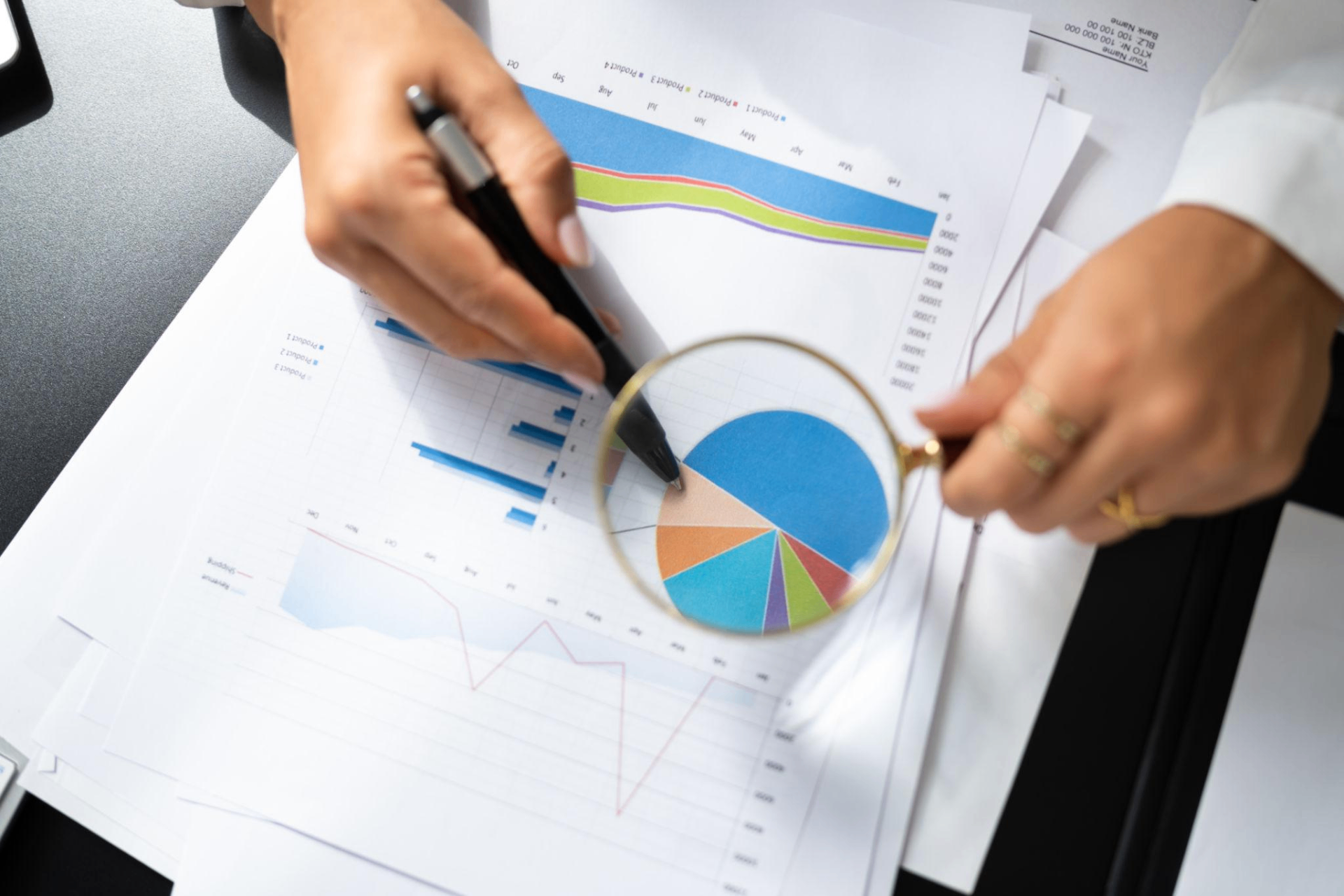 Magnifying glass examining documents and charts during a background verification analysis