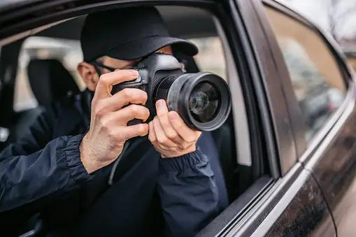 Investigator conducting discreet surveillance from a vehicle with a long-lens camera